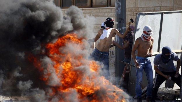 Masked Palestinian protesters throw stones at Israeli police during clashes in the Shuafat neighbourhood in East Jerusalem, on 2 July 2014,