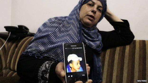 Suha, mother of Mohammed Abu Khdair, shows a picture of her son on her mobile phone at their home in Shuafat, an Arab suburb of Jerusalem on 2 2014.