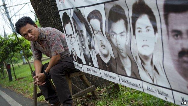 Indonesian torture victim Mugiyanto sits beside a banner showing portraits of missing activists displayed outside the National Commission on Human Rights in Jakarta on 30 May 2014