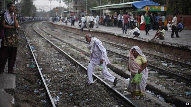 Indian people cross a railway track in Delhi, India.