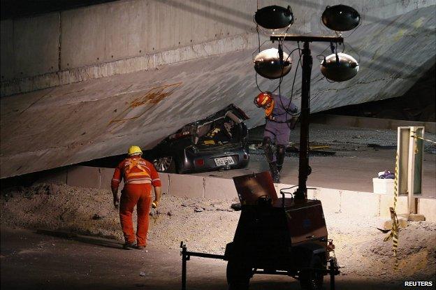 Rescue workers inspect a car trapped underneath the rubble in Belo Horizonte - 3 July 2014