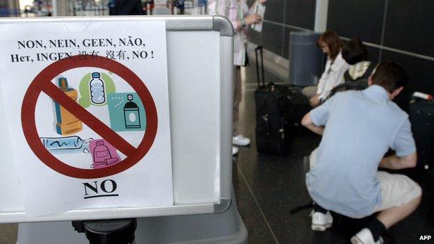 A group of travellers repack their baggage just before entering the security checkpoint to comply with new US air travel regulations prohibiting liquids in carry-on luggage, 10 August, 2006