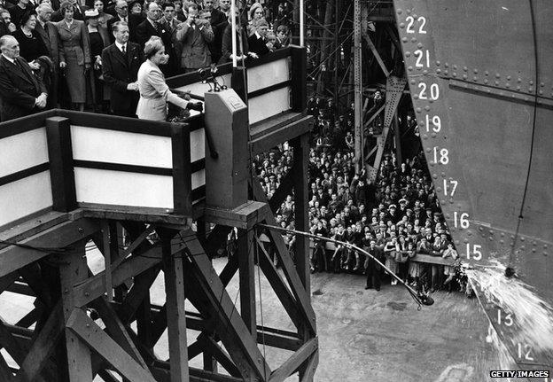 Mrs Leif Egeland, wife of the South African High Commissioner, smashes a bottle against the Intermediate Class liner MV 'Bloemfontein Castle' at the Harland and Wolff shipyard in Belfast