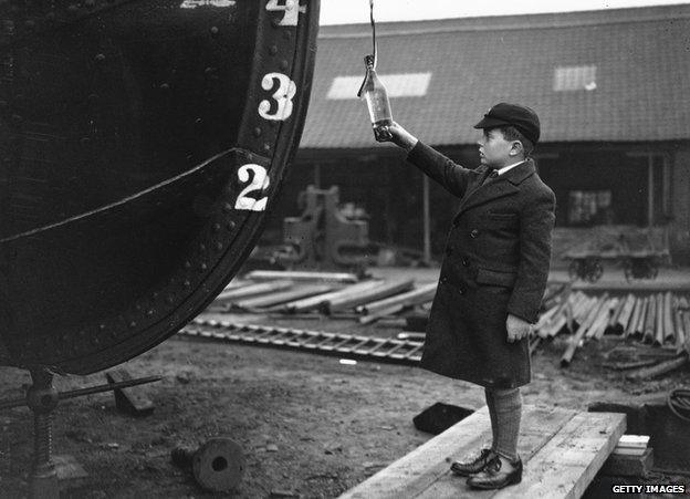 A boy prepares to smash a bottle against his boat