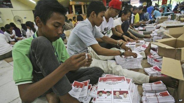 Workers fold ballots bearing portraits of Indonesian presidential candidates (L-R) Prabowo Subianto with his running mate Hatta Rajasa and Joko Widodo with his running mate Jusuf Kalla