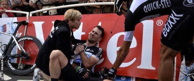 Mark Cavendish holds his injured shoulder