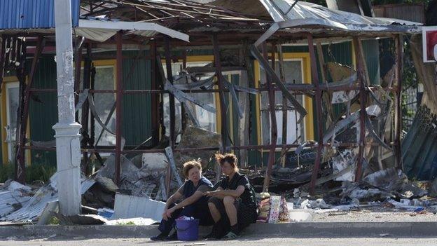 Women sit near a destroyed shop in the city of Sloviansk, July 5