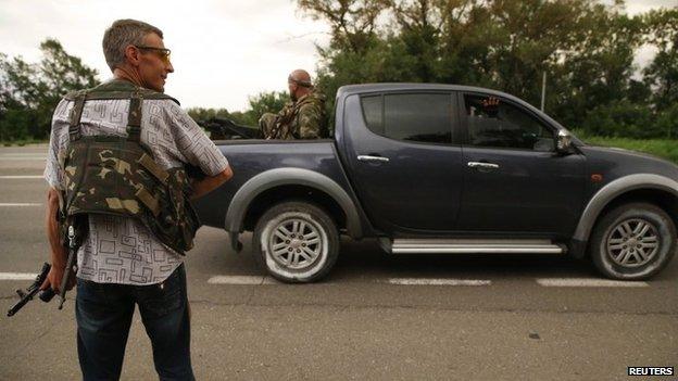 An armed pro-Russian rebel stands on the road as others drive past near the eastern Ukrainian city of Donetsk July 5