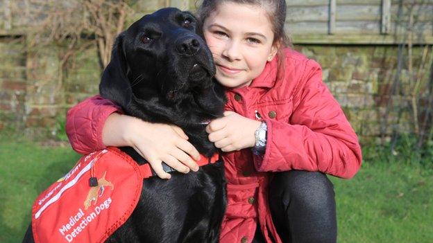 A young girl Gemma hugging Polo, her medical detection dog