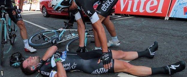 Cavendish lies injured as an Omega Pharma - Quick-Step team-mate looks over him