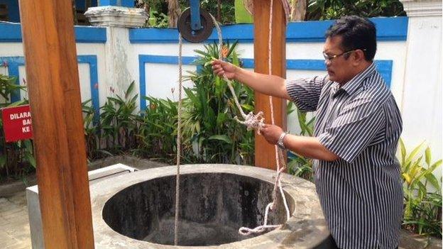 Museum keeper Gatot Nugroho draws water from a well