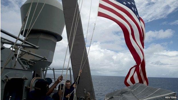 US Navy personnel raise their flag during Cooperation Afloat Readiness and Training (CARAT) Philippines 2014, a US-Philippines military exercise, aboard USS John S. McCain in the South China Sea near waters claimed by China on 28 June 2014.