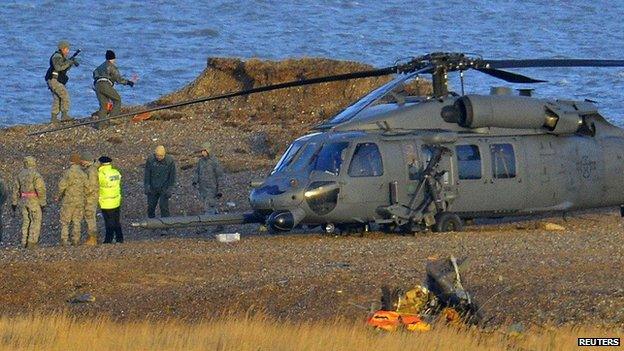 A Pave Hawk helicopter, military personnel and emergency services attend the scene of a helicopter crash on the coast near the village of Cley in Norfolk