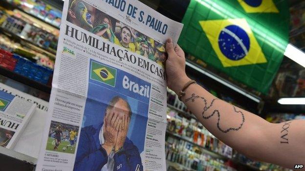 A passer-by looks at the front page of a newspaper on display at a news stand in Sao Paulo on 9 July, 2014.