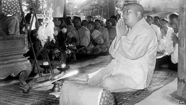 Former Cambodian King Norodom Sihanouk prays with monks after abdicating in 1955