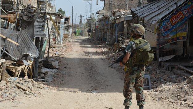 Soldier stands on empty road lined with destroyed buildings in Miranshah