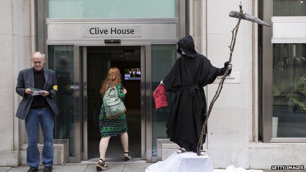 A man dressed as the Grim Reaper stands on a union picket line