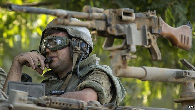 An Israeli soldier stands on an armoured personnel carrier (APC) vehicle positioned along the southern Israeli border with the Gaza Strip on 10 July 2014