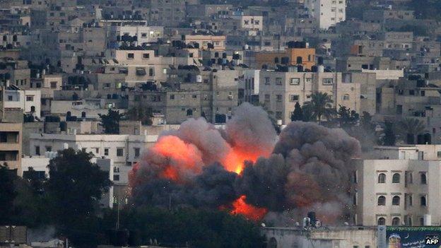 Flames erupt from a building hit by an Israeli air strike on 9 July 2014 in Gaza City.