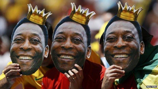 Brazilian fans hold Pele masks during an Argentina-Belgium match