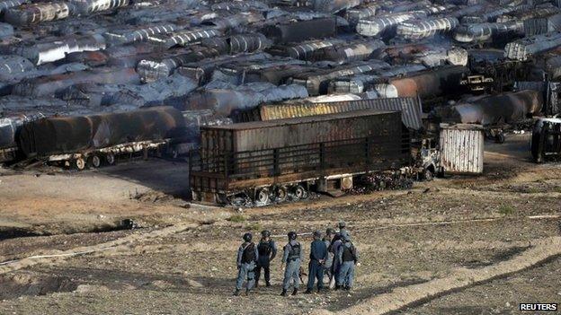 Afghan policemen stand at the site of burning fuel trucks after an overnight attack by the Taliban on the outskirts of Kabul July 5, 2014.
