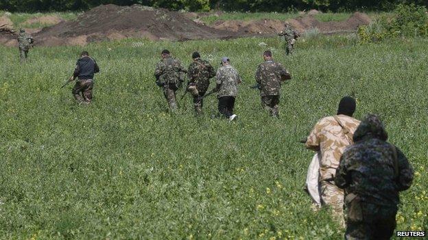 Pro-Russian separatist fighters walk towards a checkpoint in the eastern Ukrainian city of Donetsk (10 July 2014)