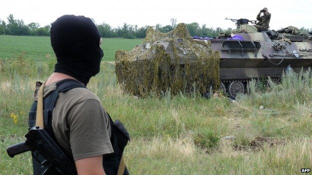 A Ukrainian government soldier stands near an armoured vehicle some 20km south of Donetsk