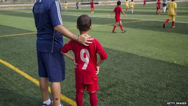 A coach from Real Madrid stands with a young Chinese student before subbing him to a training match at the Evergrande International Football School on 14 June, 2014 near Qingyuan in Guangdong Province, China