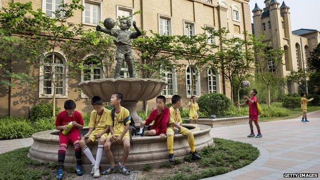 Young Chinese football players sit together in the campus as they wait to head to training at the Evergrande International Football School on 14 June, 2014 near Qingyuan in Guangdong Province, China