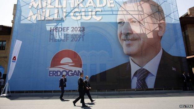 Security officers walk pass by a huge election banner of Mr Erdogan in Istanbul (11 July 2014)