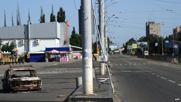 An empty street and a burned-out car near a bus station in Luhansk (12 July 2014)