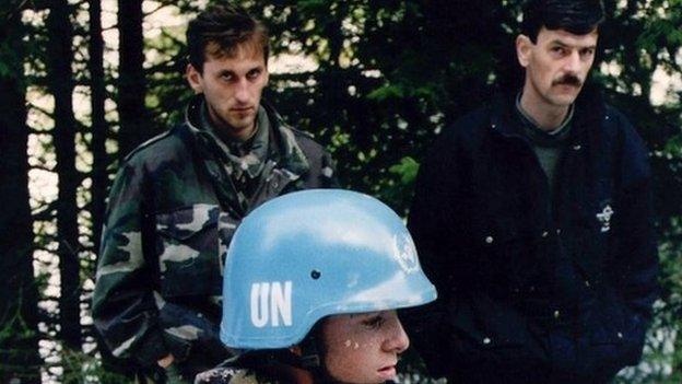 A Dutch UN peacekeeper standing near two unidentified Bosnian men in Srebrenica (1994)