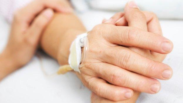 Two people holding hands in hospital bed