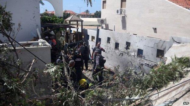 Emergency workers and Israeli security check a house damaged by a rocket fired by militants from Gaza on July 16, 2014, in the city of Ashkelon