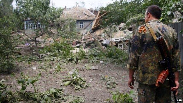 A pro-Russian militant looks at a destroyed house in Snizhne, eastern Ukraine