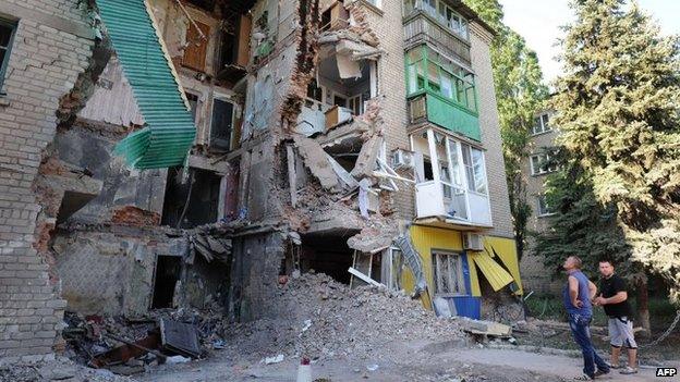 Men look at a building destroyed by the Ukrainian Air Force in Snezhnoye, 80 km east of Donetsk, on July 16