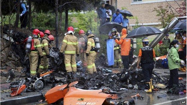 Firefighters inspect the wreckage of a helicopter which crashed near an apartment complex and school in Gwangju, South Korea, Thursday, on 17 July 2014.