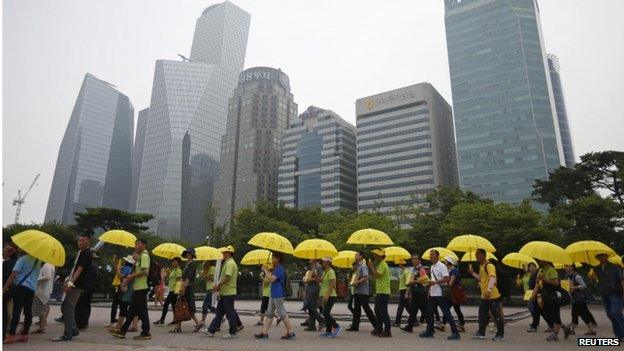 People holding yellow umbrellas in support of victims of the mid-April Sewol ferry disaster, carry boxes containing signatures of South Koreans petitioning for the enactment of a special law after the disaster, as they march towards the National Assembly at Yeouido Park in Seoul on 15 July 2014.