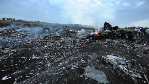 People stand next to the wreckages of the MH17 machine (18 July 2014)