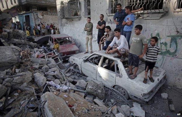 Palestinians look at the damage of a destroyed house in Rafah refugee camp, southern Gaza Strip