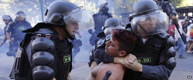 A protestor is restrained by police in Rio on 13 July