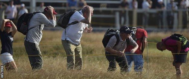 Spectators take cover to avoid a wayward tee shot from Tiger Woods