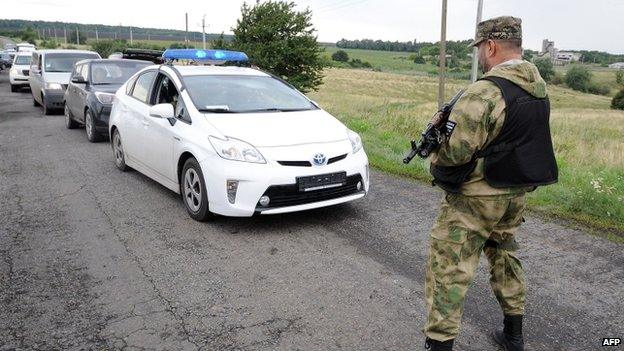 A man wearing military fatigue stops traffic near the site of the crash of a Malaysia Airlines plane