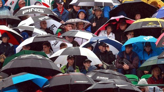 Golf fans sheltering under umbrellas