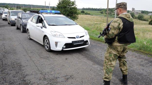 An armed man stops traffic near the site of the crash of a Malaysia Airlines plane in rebel-held east Ukraine, on 19 July 2014