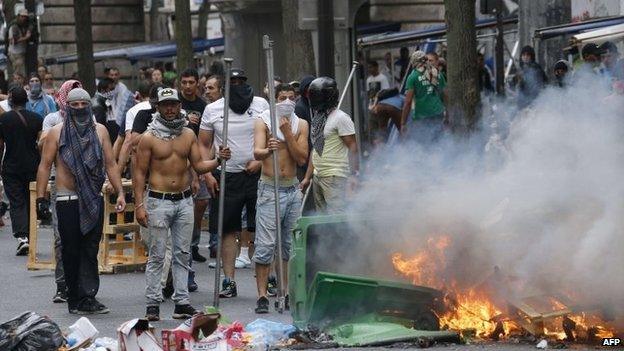 Protesters stand in front of burning bin near the aerial metro station of Barbes-Rochechouart, in Paris, 19 July 2014