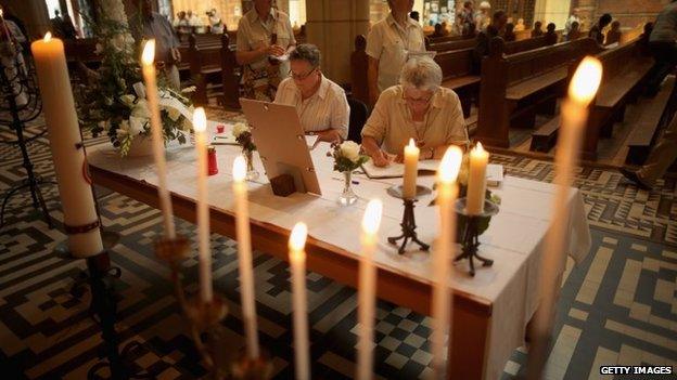 People sign a book of condolence during a special mass in Saint Vitus church in memory of the victims of Malaysia Airlines flight MH17, in Hilversum, Netherlands, 20 July 2014