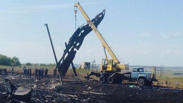 A crane at the crash site lifting large pieces of debris, 20 July 2014