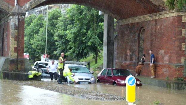 Cars stuck in flood water under a bridge