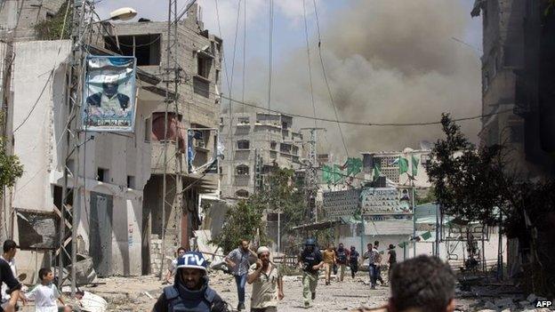 Smoke and dust rises as Palestinians flee an Israeli military attack on the Shejaiya neighbourhood between Gaza City and the Israeli border, 20 July 2014